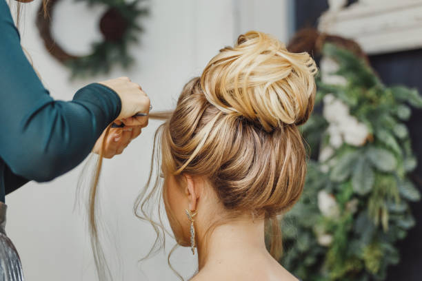 parrucchiere realizza un chignon superiore acconciatura complesso e bello. adatto per lo stile serale e nuziale.